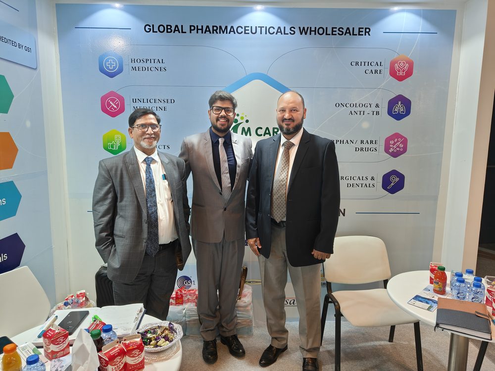 M Care Arab Health 2024 booth, "Global Pharmaceuticals Wholesaler" backdrop, three team members on stand.
